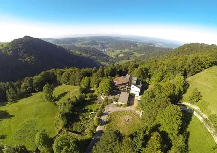 Das Hotel Wasserfallen aus der Luft, umgeben von Wald und Wiesen im Jura